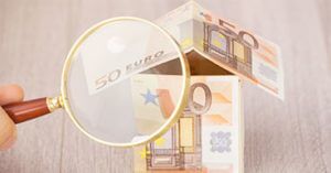 Haus aus 50 Euro Scheinen unter einer Lupe